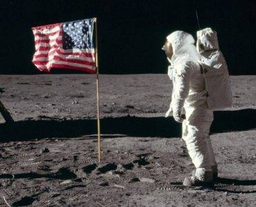 Astronaut facing flag on moon