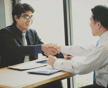 Men shaking hands across table